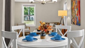 A dining area with a white table, blue bowls, and a vase with flowers.