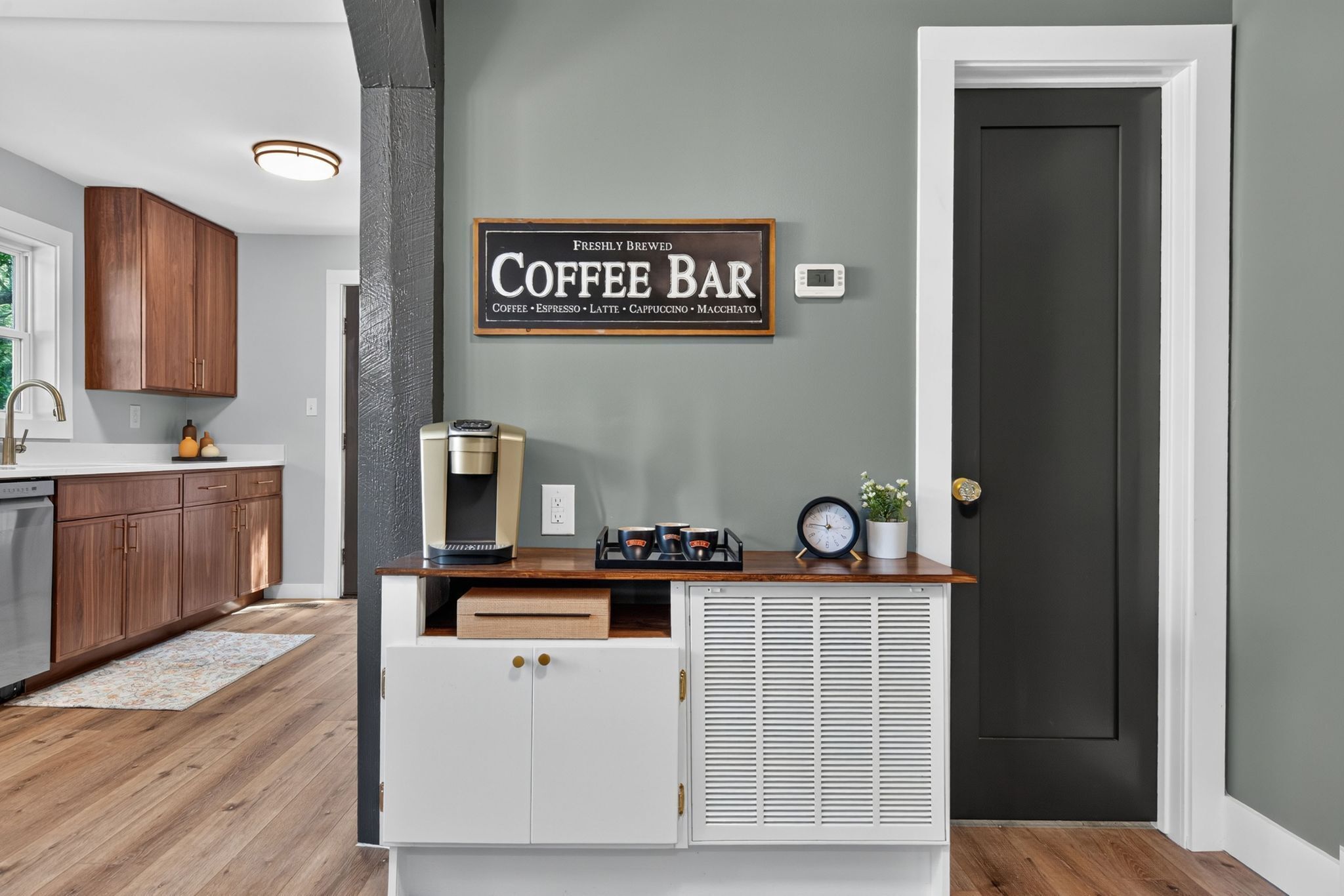 Una cocina con armarios de madera, un letrero de barra de café, una cafetera y un reloj.
