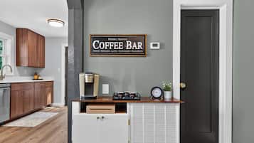 Una cocina con armarios de madera, un letrero de barra de café, una cafetera y un reloj.