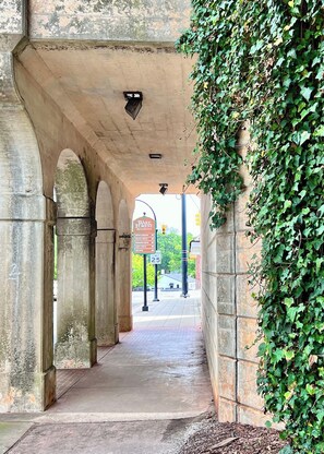Una construcció de pedra amb arc i una passeig inferior, un senyal de carrer i una paret coberta de vital.