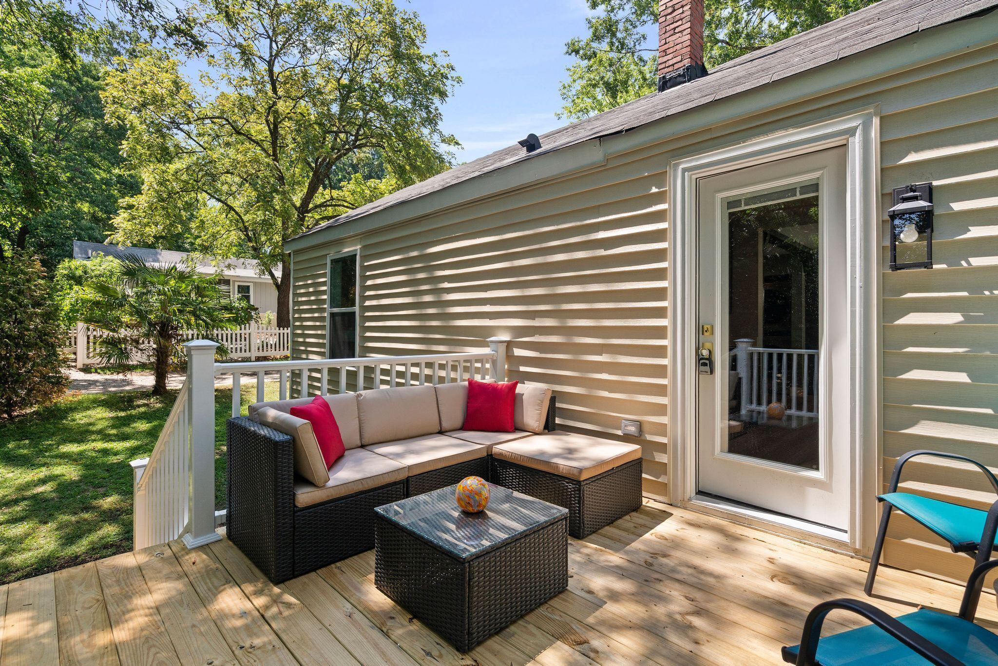 A covered outdoor patio with a sofa, a table, and a chair.
