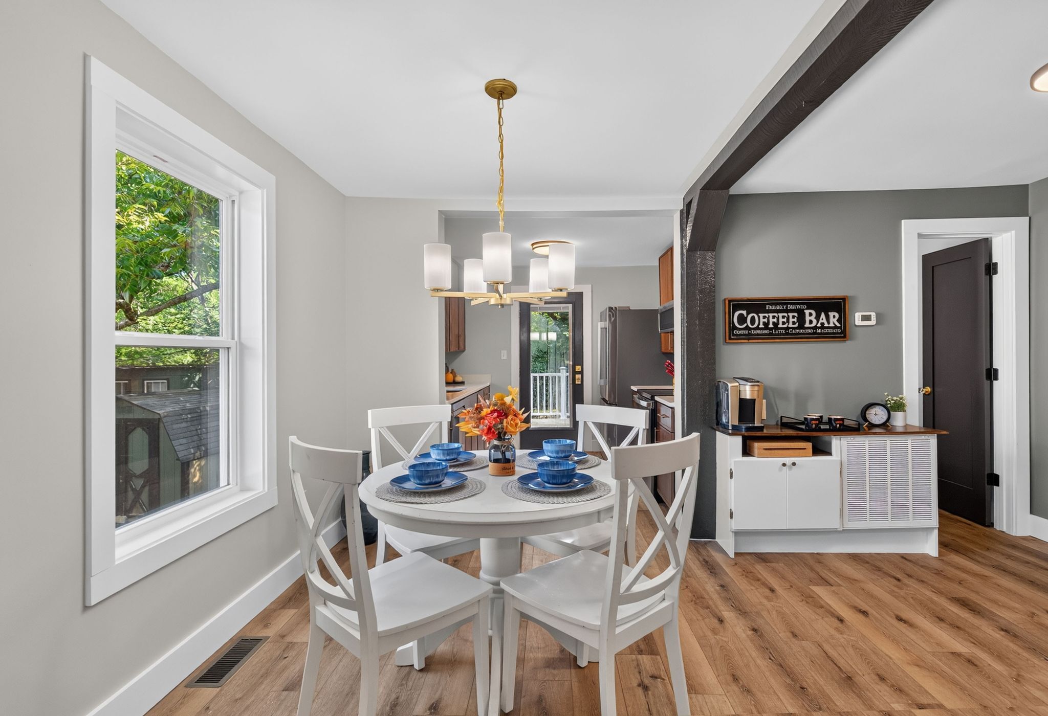 A modern kitchen with a dining area, featuring a coffee bar and a view of the outdoors.