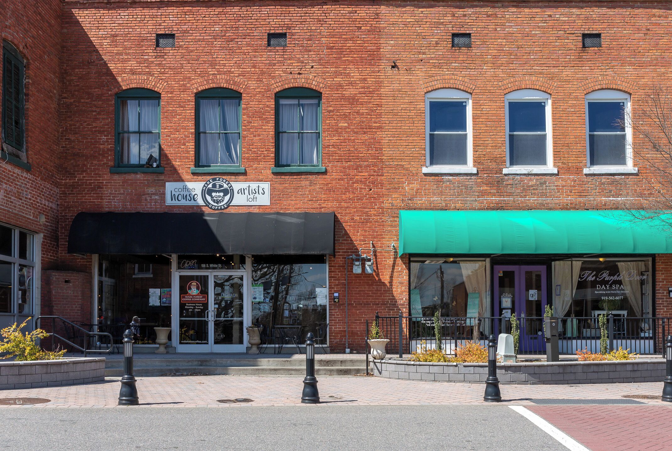 A brick building with a coffee house and loft sign, a spa, and a green awning.