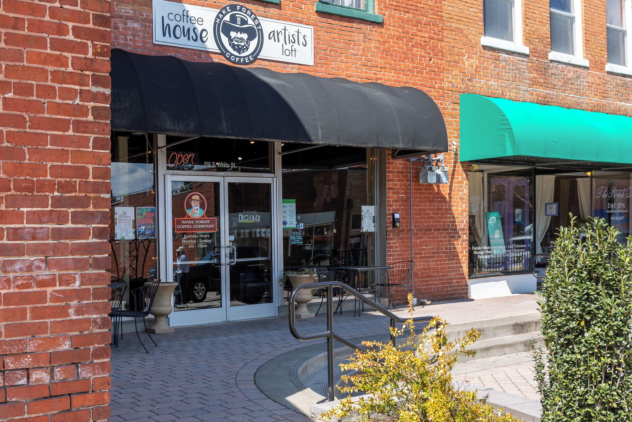 A coffee shop with a black awning, outdoor seating, and a visible entrance.