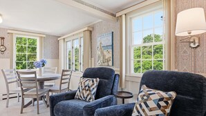 Una habitación con una mesa de comedor, dos sillones, una mesita redonda y un cuadro de un faro.