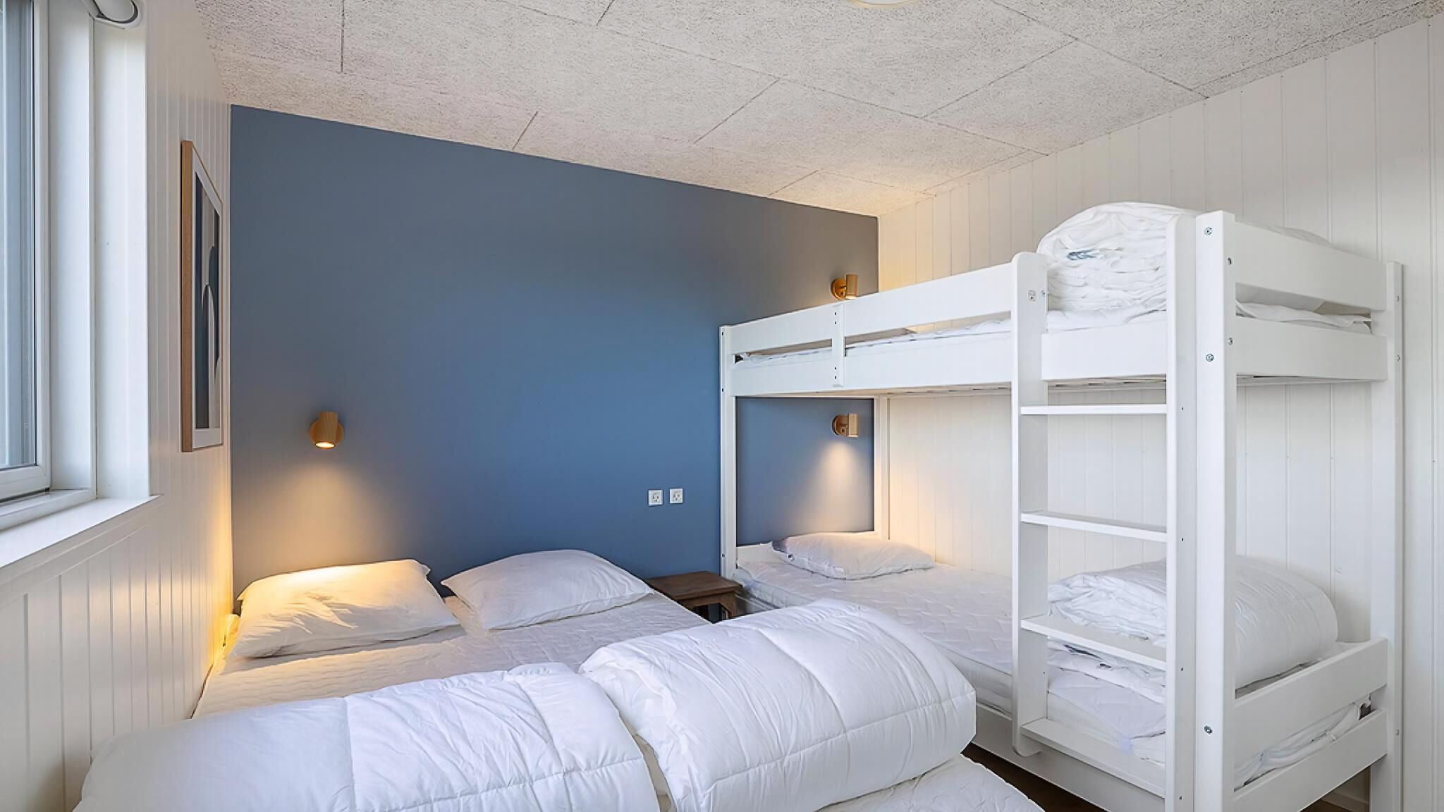 Una habitación con literas, una ventana y luces en la pared.