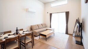 A modern living room with a sofa, coffee table, and dining area. - North Point Kamifurano (Sorachi-gun,Kamifurano-cho)