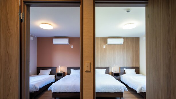 A mirrored room with two beds, nightstands, and wall-mounted air conditioning units. - North Point Kamifurano (Sorachi-gun,Kamifurano-cho)