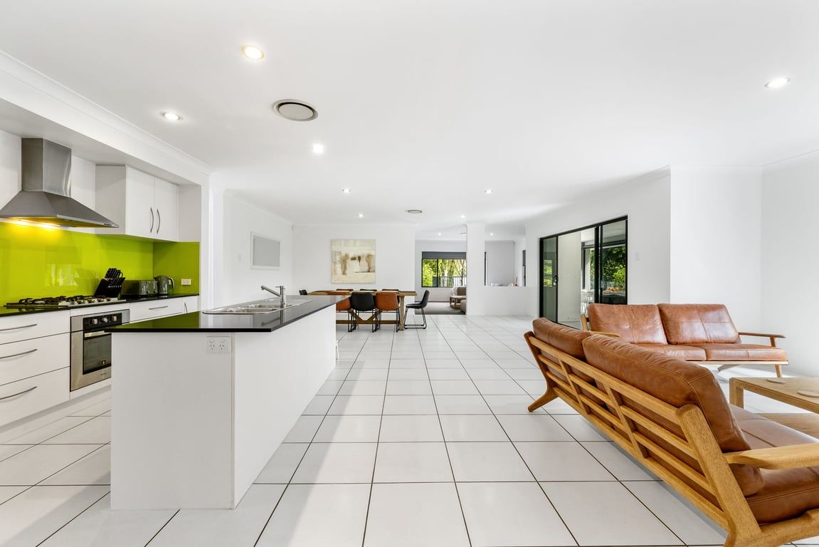 A modern kitchen with white cabinetry, a green backsplash, and a central island.