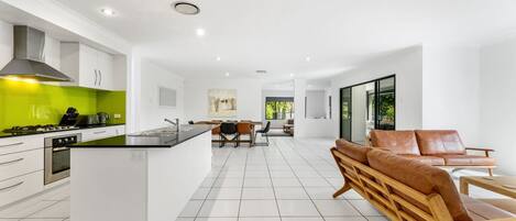 A modern kitchen with white cabinetry, a green backsplash, and a central island.