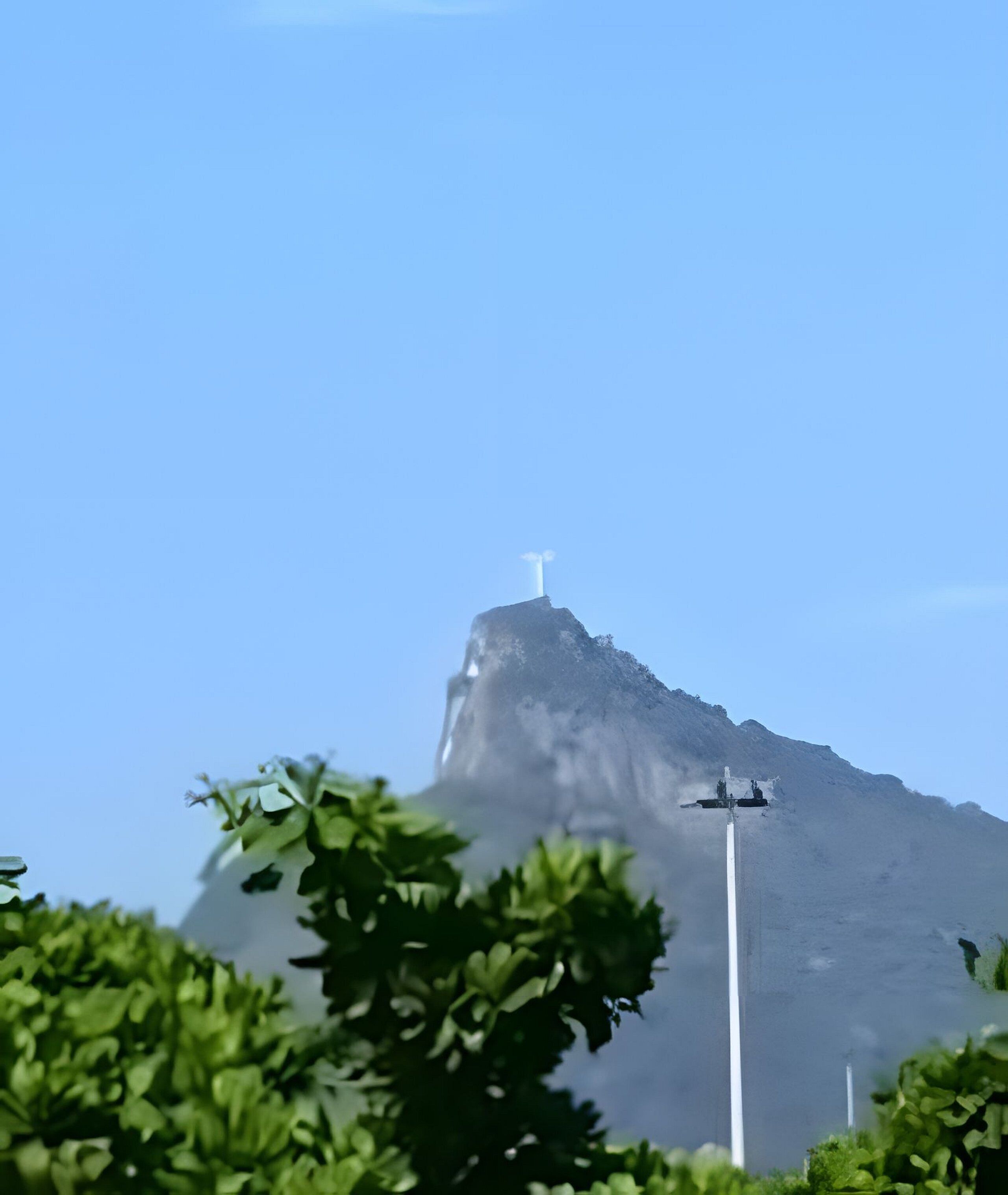Ein Berg mit einer weißen Struktur auf der Spitze, umgeben von Grün.
