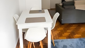 Um espaço de estar compacto com uma mesa de jantar, cadeiras, sofá, televisão de tela plana e ventoinha no teto.