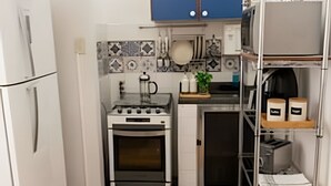 Cozinha compacta com fogão branco, armários azuis e painel de azulejos.