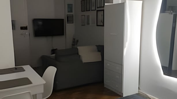 Um espaço de estar compacto com cozinha compacta, televisão de tela plana, sofá e área de jantar.