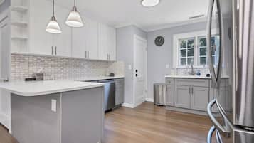 A modern kitchen with a central island, pendant lighting, and a stainless steel refrigerator.