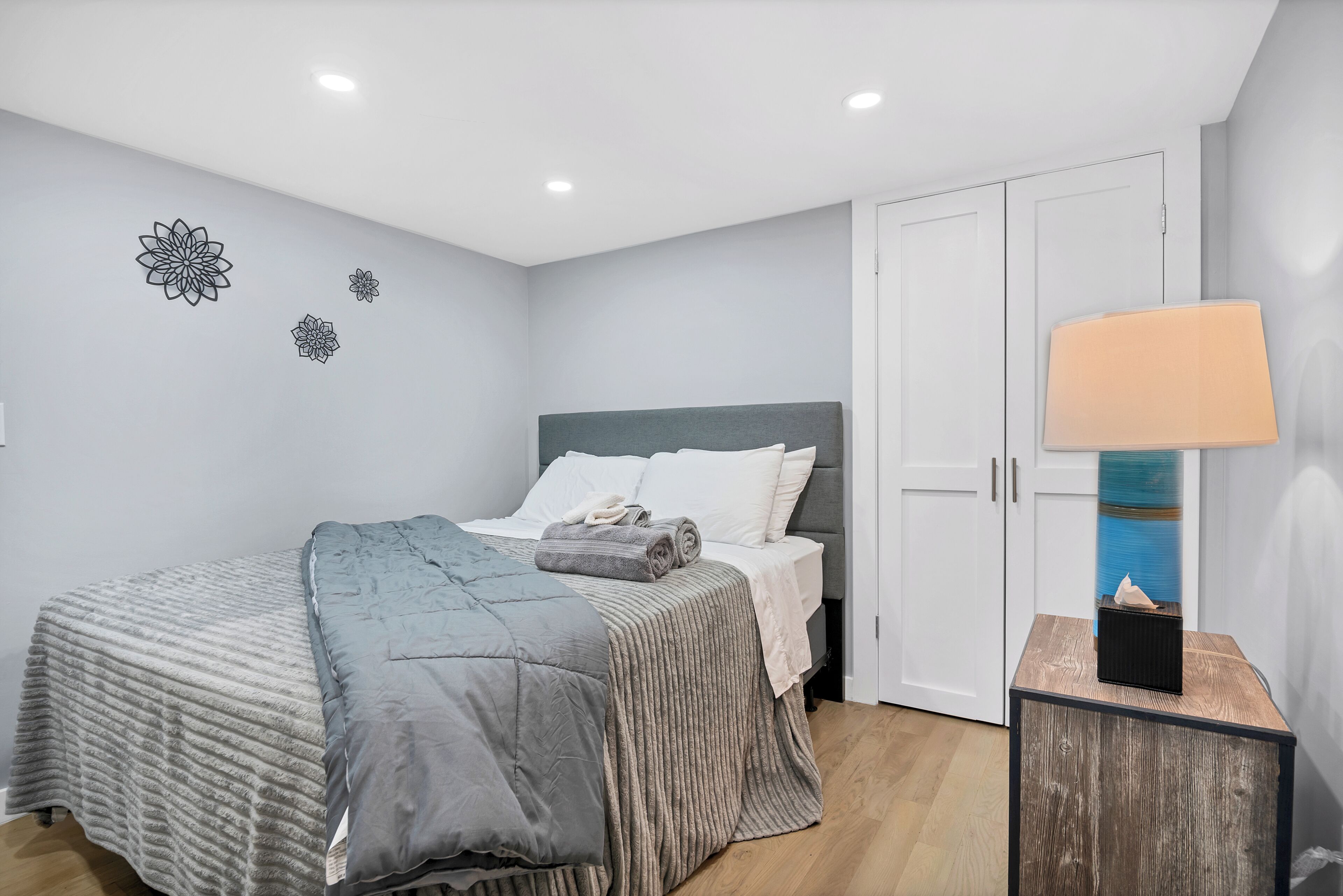 A bedroom with a bed, a bedside table with a lamp, and a wardrobe.
