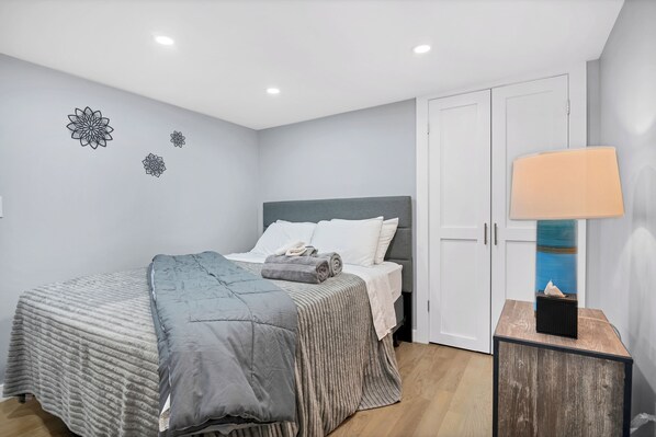 A bedroom with a bed, a bedside table with a lamp, and a wardrobe.