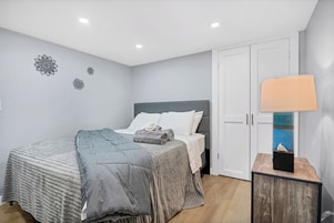 Un dormitorio con cama, mesita de noche con lámpara y armario.