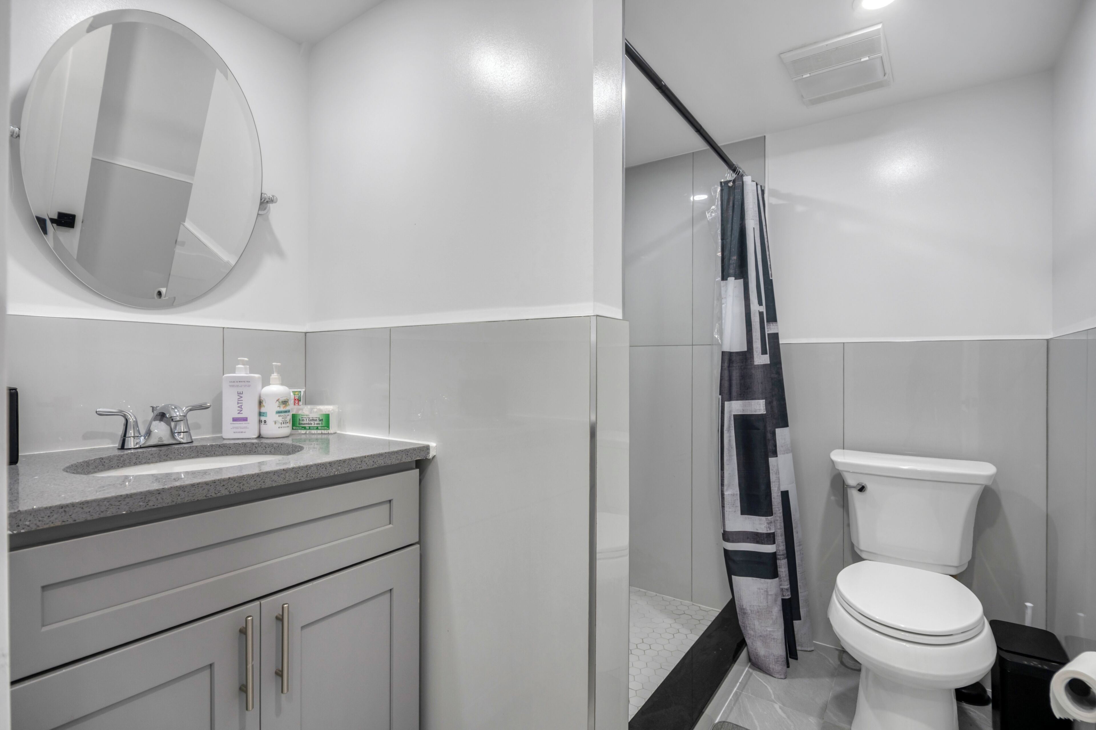 A modern bathroom with a toilet, sink, and mirror.