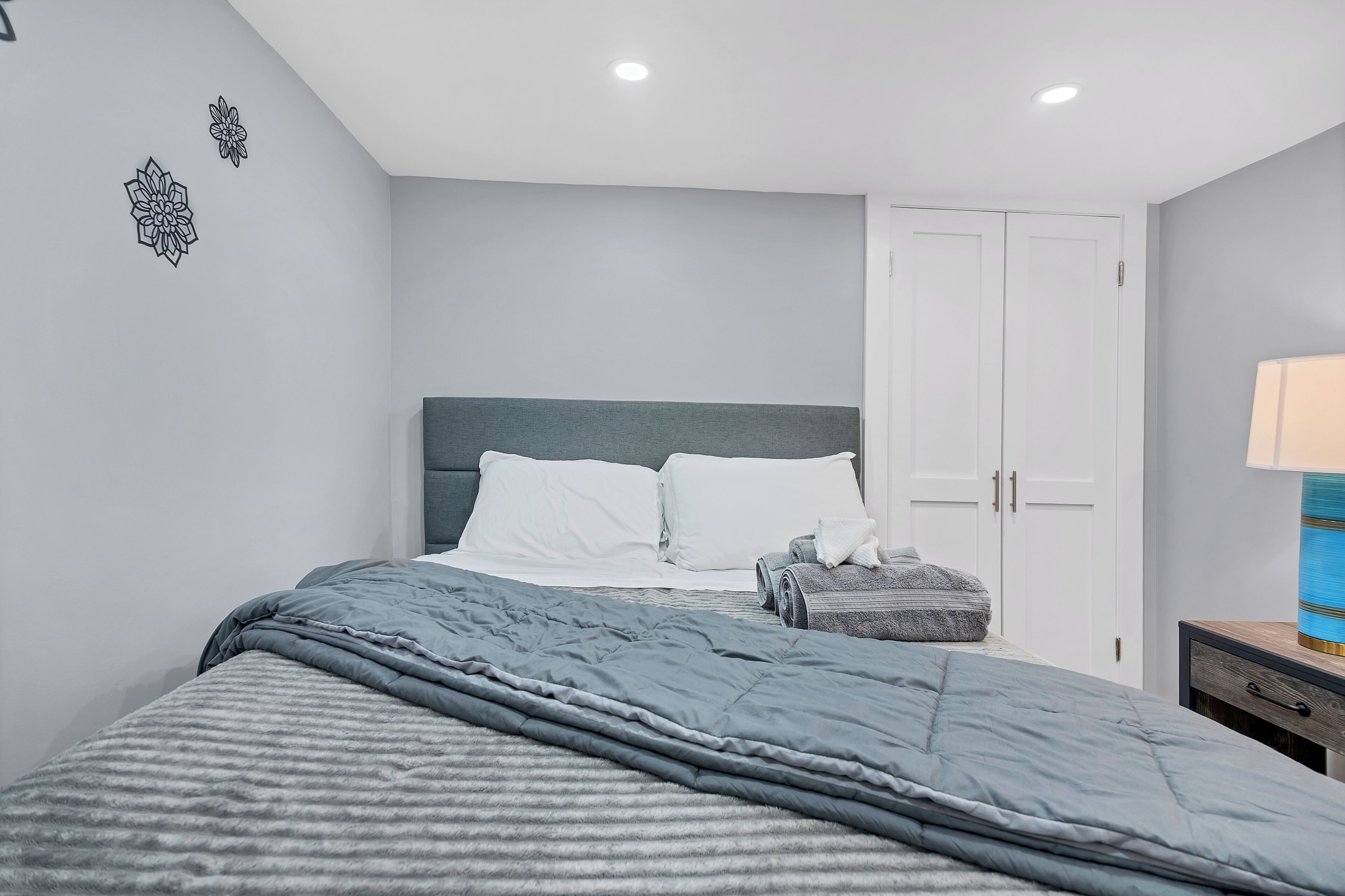 A bedroom with a bed, a nightstand, a lamp, and a wardrobe.