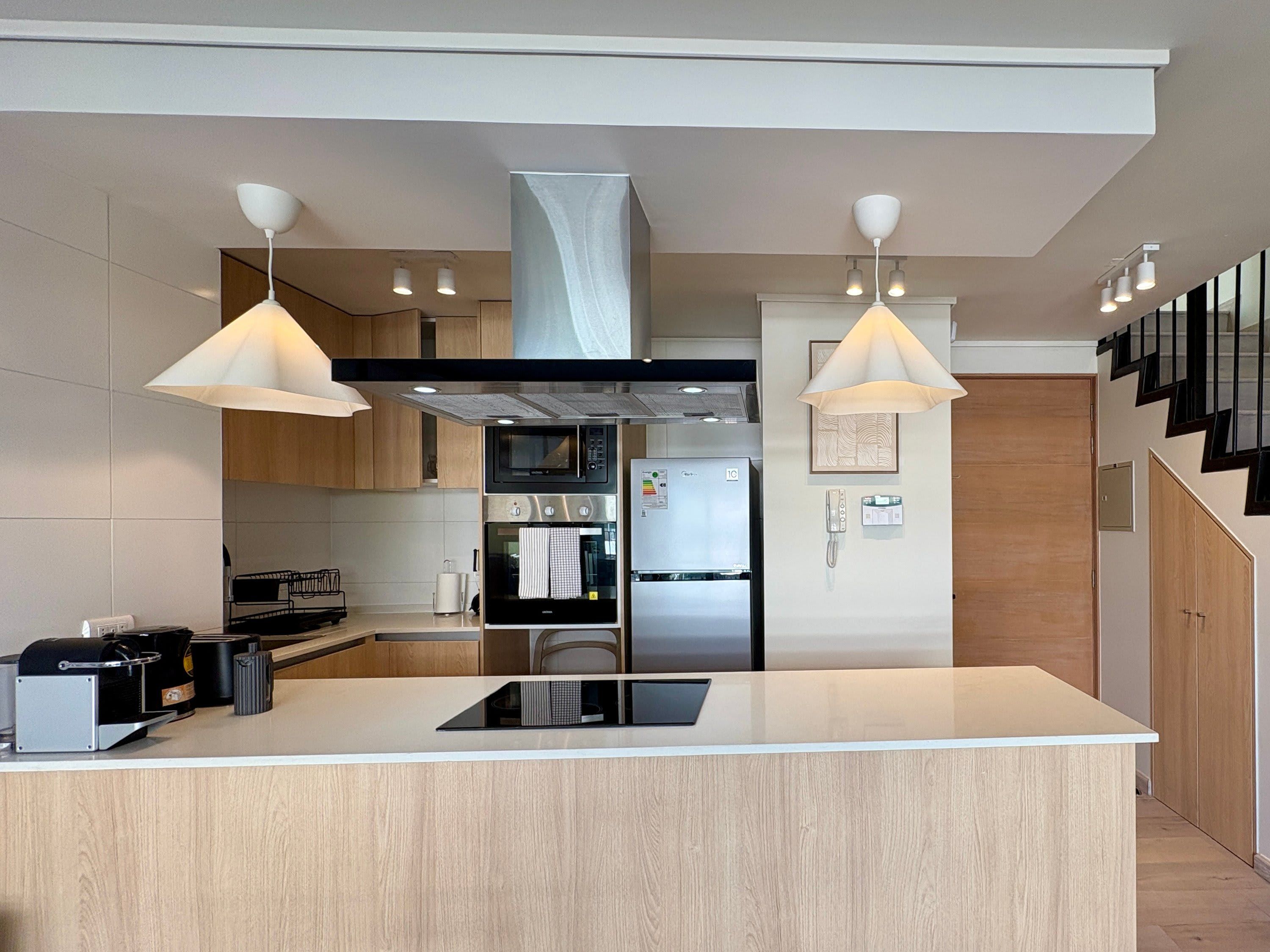 A modern kitchen with a central island, stainless steel appliances, and pendant lighting.
