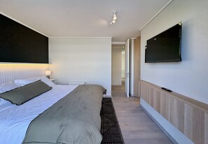 A modern hotel room with a bed, a flat-screen TV mounted on the wall, and a visible door leading to another room. - Providencia Duplex - A/C, Balcony, Gym & Parking (Providencia)