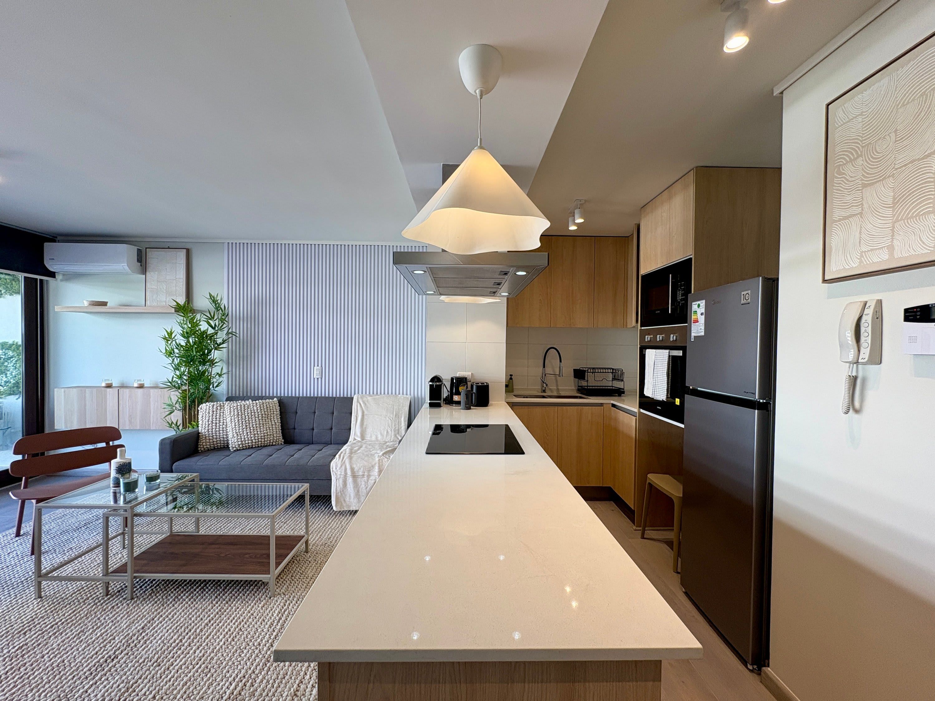 Una cocina moderna con una isla central, armarios de madera y horno empotrado.