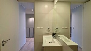 Ein modernes Badezimmer mit einem großen Spiegel, zwei Waschbecken und einer begehbaren Dusche.