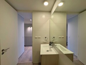 Un baño moderno con un espejo grande, dos lavamanos y una ducha a ras de suelo.