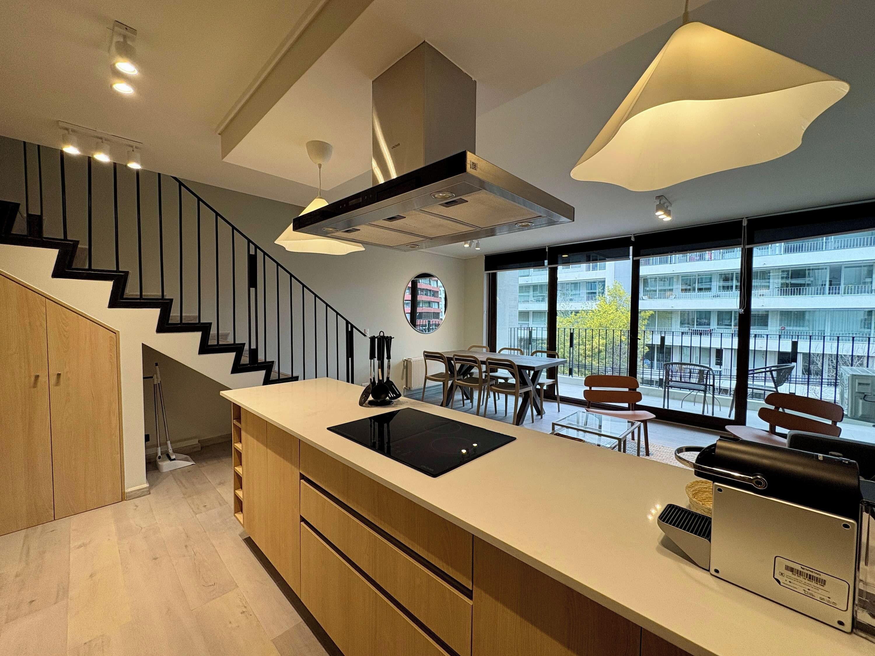 A modern kitchen with a central island, built-in appliances, and a dining area with a view of the city.