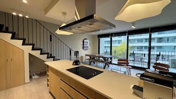 A modern kitchen with a central island, built-in appliances, and a dining area with a view of the city.