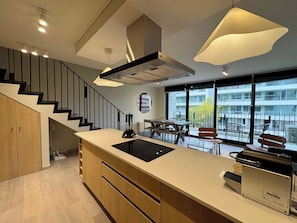 A modern kitchen with a central island, built-in appliances, and a dining area with a view of the city.