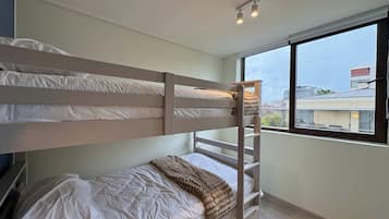 A bunk bed room with a window, a radiator, and a small rug.
