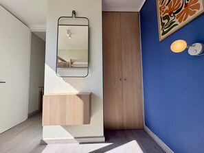 A bathroom with a wooden vanity, a mirror, and a wall-mounted light fixture. - Providencia Duplex - A/C, Balcony, Gym & Parking (Providencia)