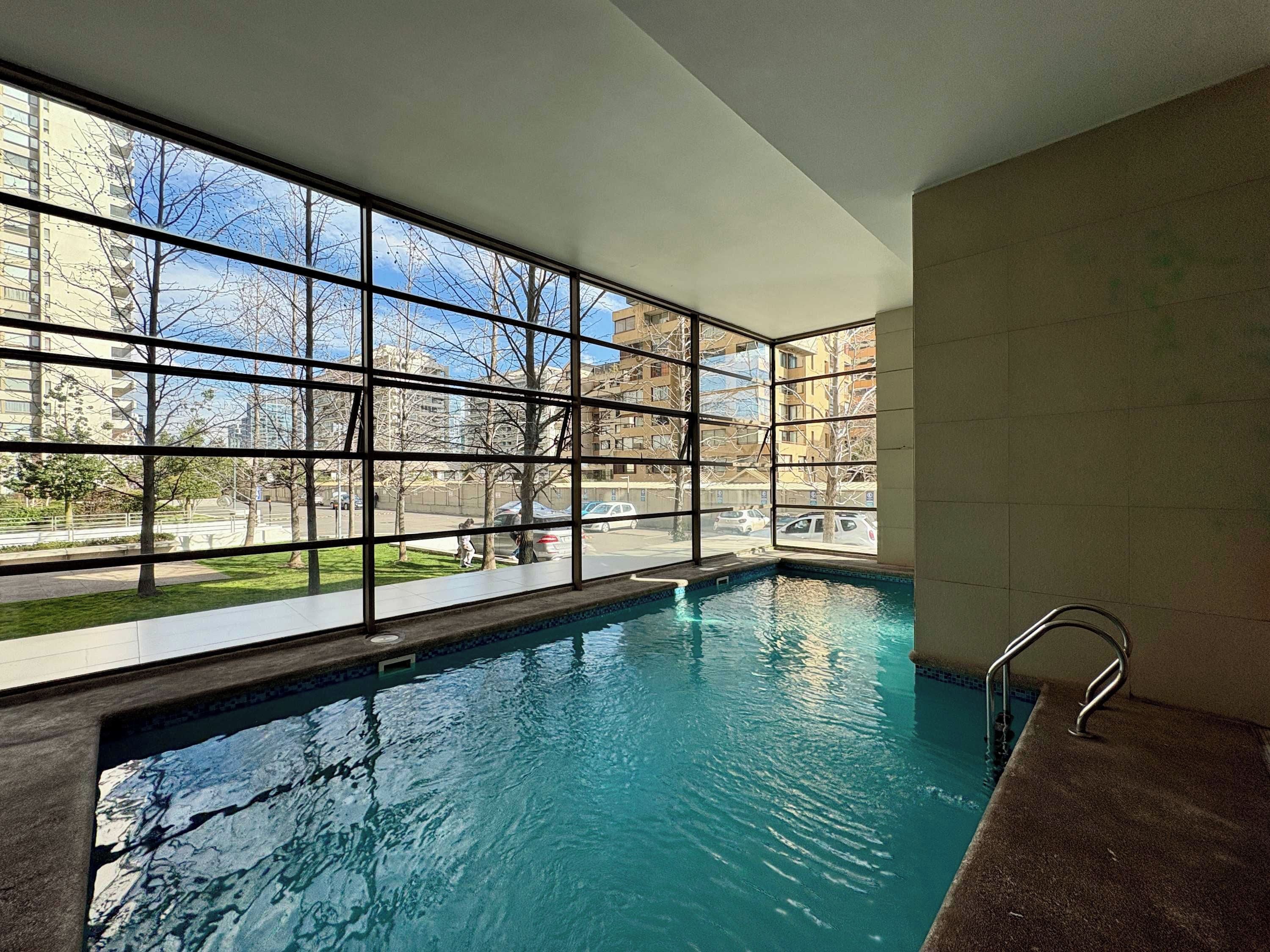 An indoor swimming pool with clear windows, a tiled floor, and a metal ladder.