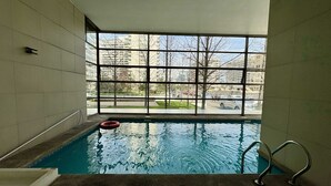 A swimming pool with clear glass walls, a lifebuoy, and a metal ladder.