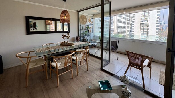 A dining area with a glass table, wicker chairs, and a ceiling light fixture.