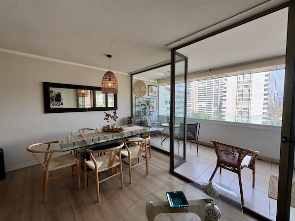 A dining area with a glass table, wicker chairs, and a ceiling light fixture.