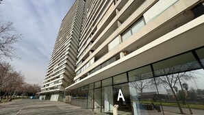 A modern multi-story building with a glass facade, a prominent 'A' sign, and a paved walkway.