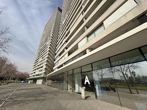 A modern multi-story building with a glass facade, a prominent 'A' sign, and a paved walkway.