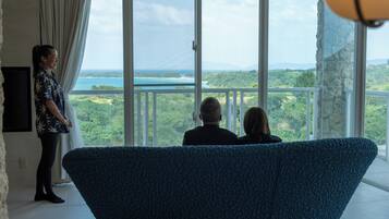 A room with a large window, a blue sofa, and a person standing by the window.