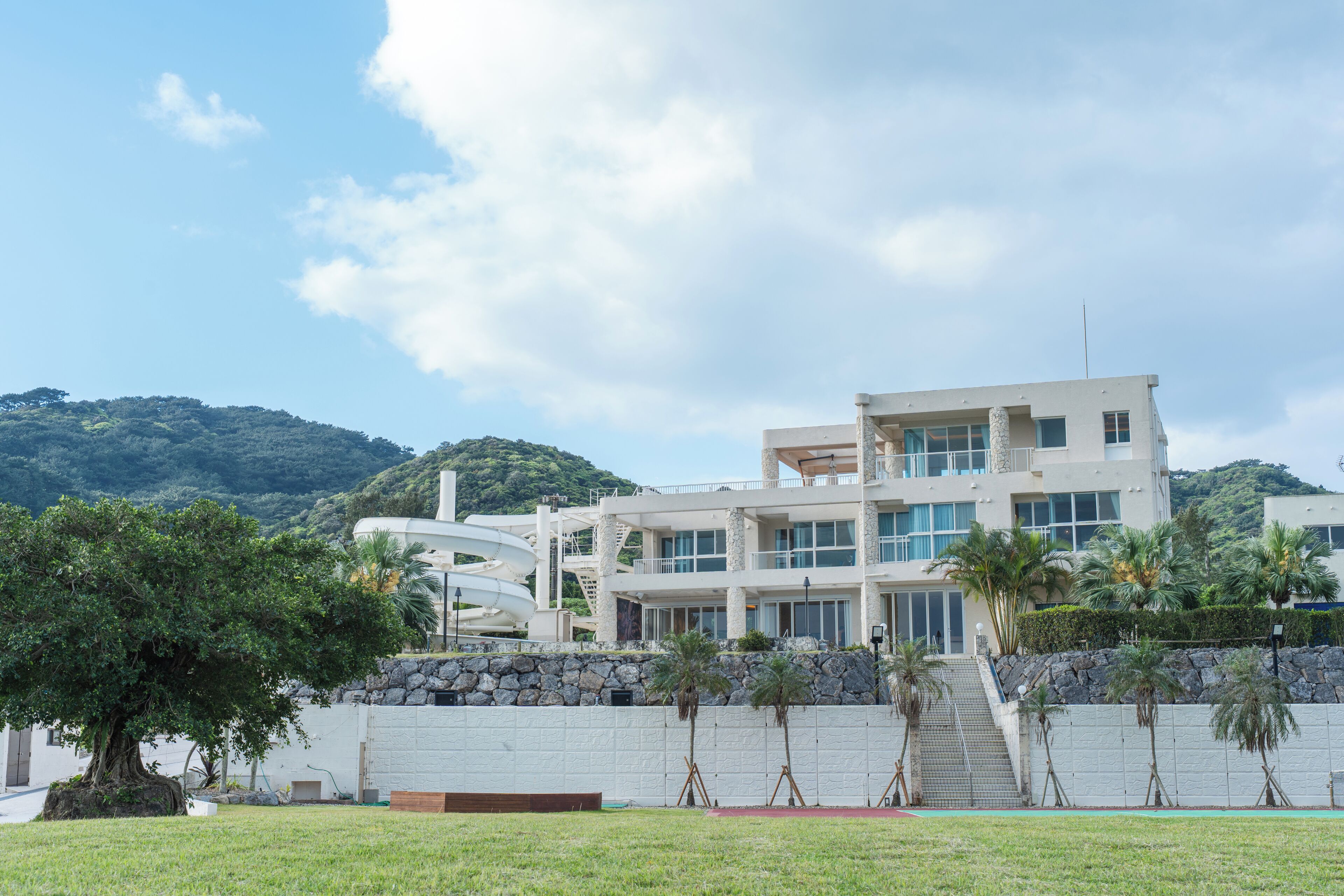 Um edifício moderno de vários andares com fachada de pedra, grandes janelas e telhado plano.