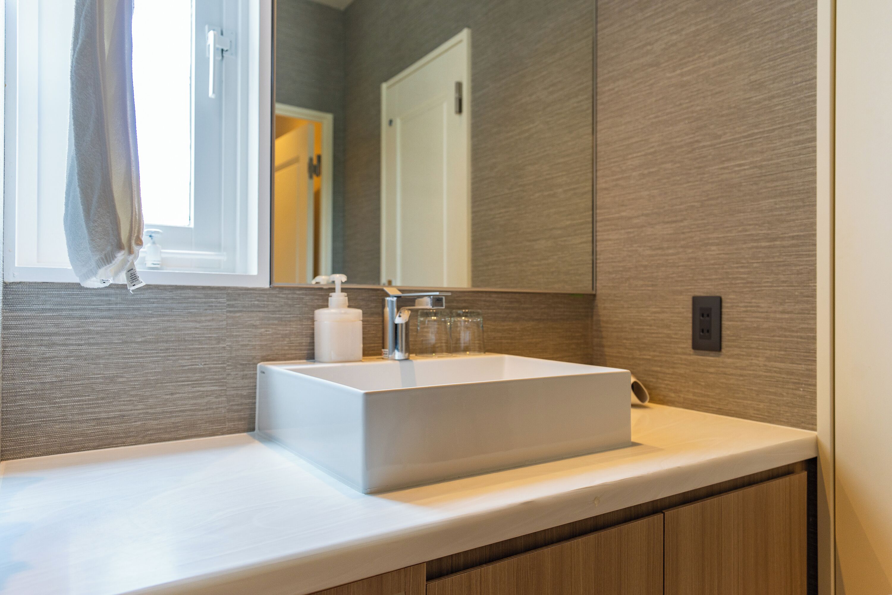 A bathroom with a white sink, a mirror, and a towel hanging on the wall.