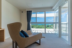 A modern living room with a sofa, a balcony with a view of the landscape, and a large window. - SEARTH KABIRA (Ishigaki)