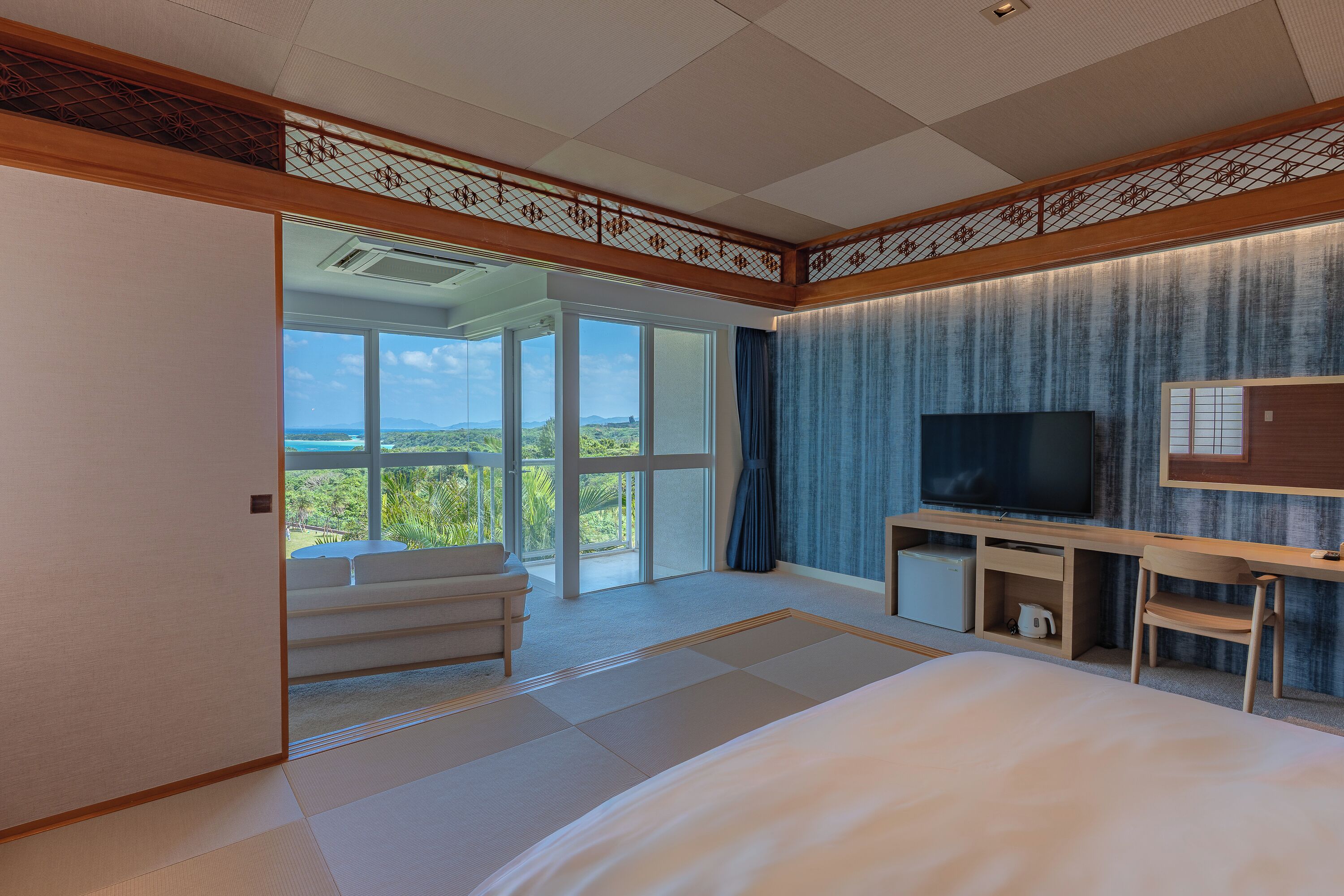 Een hotelkamer met een groot bed, een televisie, een bureau en uitzicht op de omgeving.