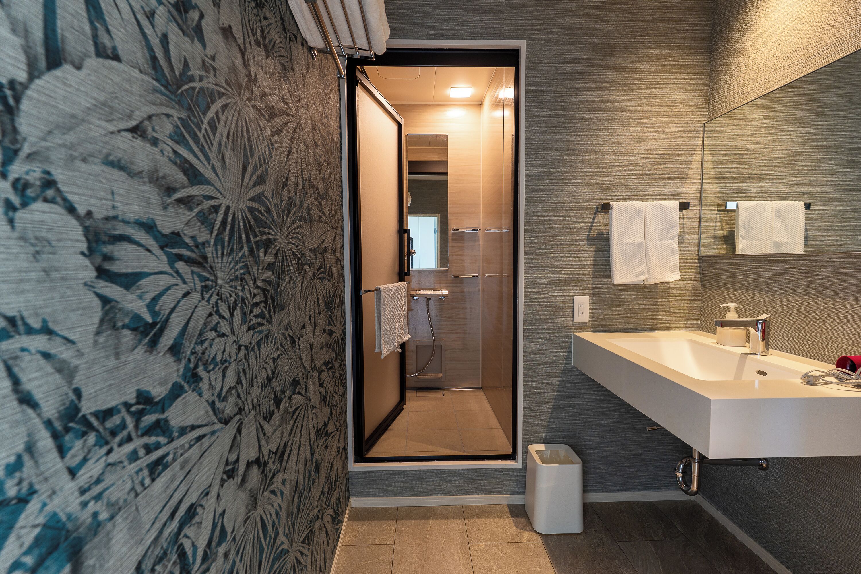 Une salle de bain moderne avec une douche, un lavabo et un miroir.