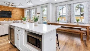 A modern kitchen with a central island, wooden flooring, and pendant lighting. - Spiny Lobster: Private beach steps away, Heated pool & spa, Golf cart, Bunk room (Miramar Beach)