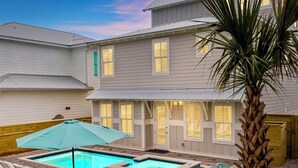 A residential property with a swimming pool, outdoor seating, and a palm tree. - Spiny Lobster: Private beach steps away, Heated pool & spa, Golf cart, Bunk room (Miramar Beach)