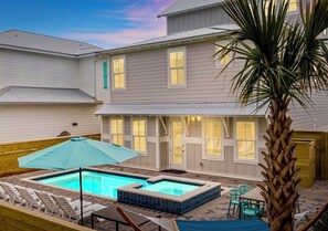 A residential property with a swimming pool, outdoor seating, and a palm tree. - Spiny Lobster: Private beach steps away, Heated pool & spa, Golf cart, Bunk room (Miramar Beach)