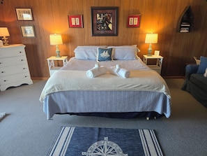 Ein Hotelzimmer mit einem großen Bett, zwei Nachttischen, einer Kommode und einer Wand mit gerahmten Bildern.